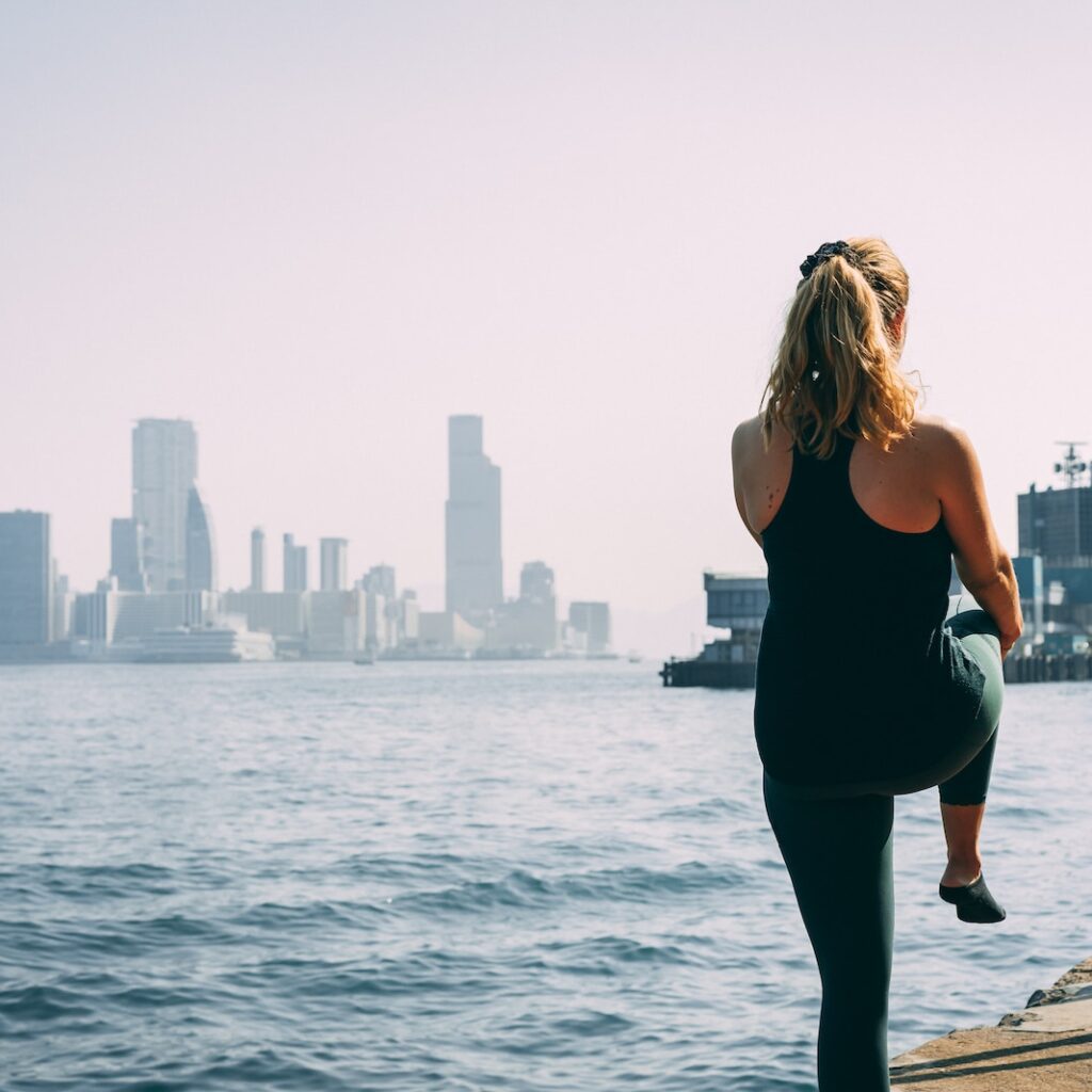 woman in black tank top and black pants standing on dock during daytime